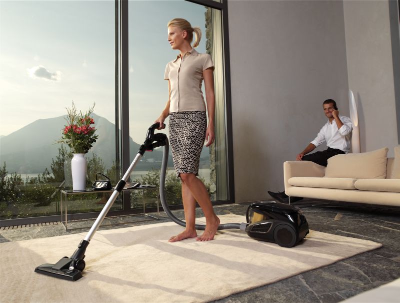 housewife with vacuum cleaner in a room